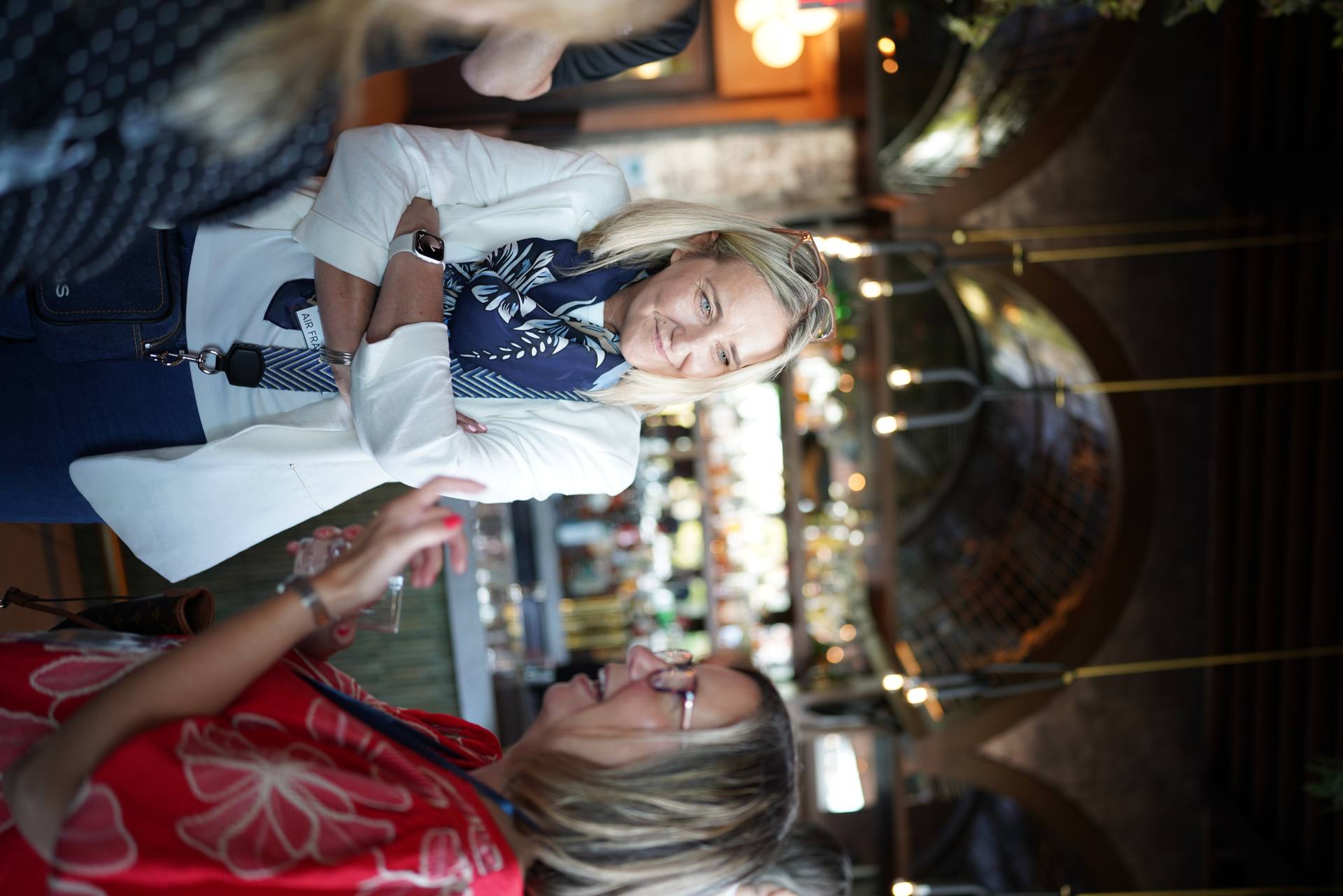 Two guests in conversation over drinks at a warmly lit corporate reception